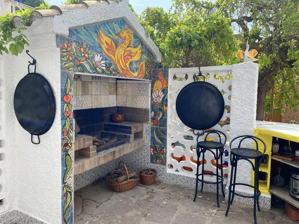 La barbacoa cerámica junto a una mesa de mosaico (trencadís) en el jardín