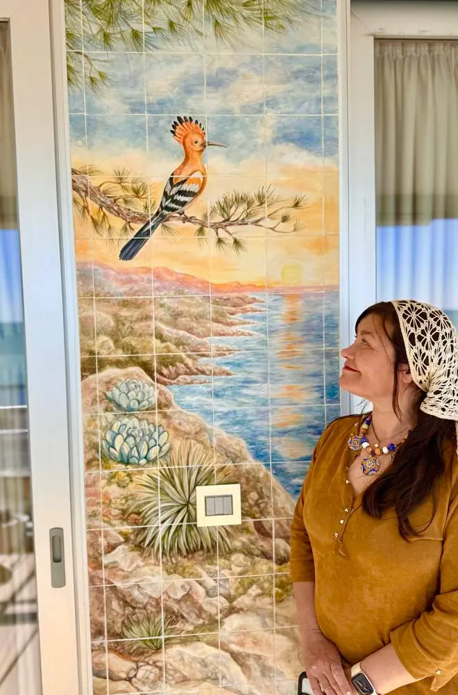 Inga Burina junto al panel cerámico «Donde las montañas tocan el cielo»