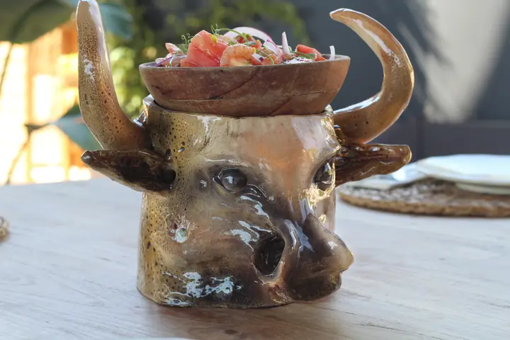 Taza cerámica en forma de cabeza de toro, servida en un restaurante